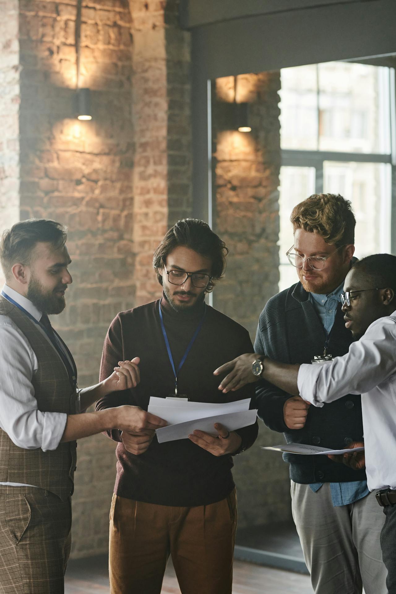 A discussion between four people. One man is holding a small stack of papers.